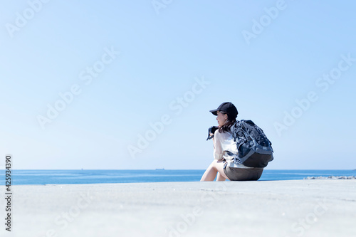 海を眺めるバックパックを背負った日本人女性