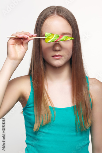 Teenager girl with with flower lollipop in hands closing eyes.