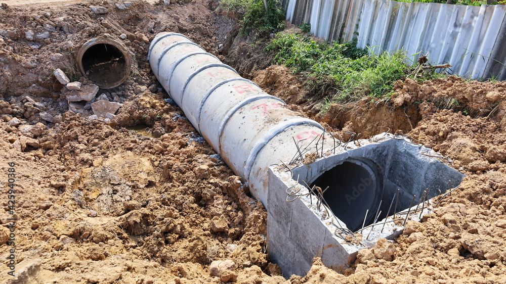 Close up mainhole and old pipe. New concrete sewer with old pipes rotted in the trench to construct a ground-based drainage system and a fence with a copy area. Selective focus Close up mainhole and old pipe. New concrete sewer with old pipes rotted in the trench to construct a ground-based drainage system and a fence with a copy area. Selective focus