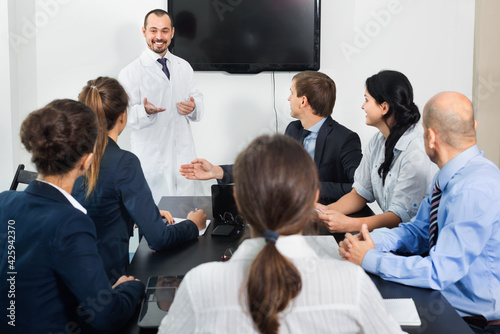 Positive smiling scientist presenting report during working meeting in office