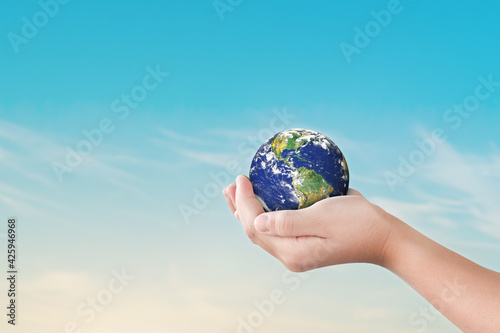 Environment day concept, Globe in child hands over blue sky background. Save of earth. Elements of this image furnished by NASA