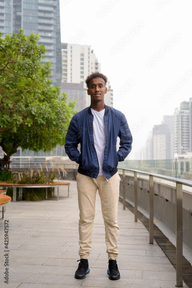 Full length shot of handsome black African man at rooftop garden Full length shot of handsome black African man at rooftop garden