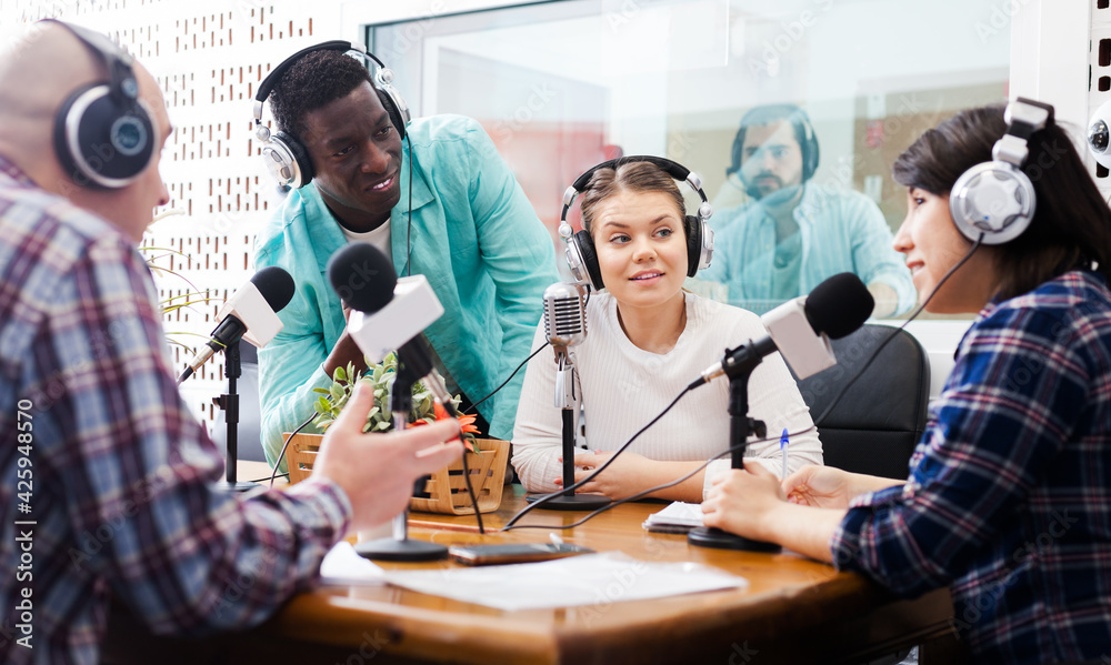 Fototapeta premium Positive male and female radio hosts interviewing guest in studio