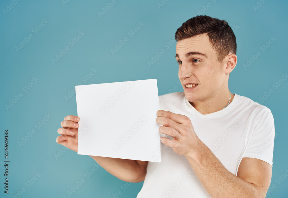Cute man with white sheet of paper on blue background cropped view mockup Cute man with white sheet of paper on blue background cropped view mockup