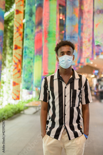 Portrait of handsome black African man wearing face mask in shopping mall