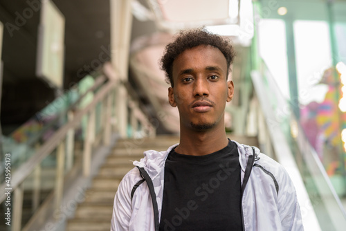 Konstfotografi Portrait of handsome black African man with cool attitude walking at stairs outd