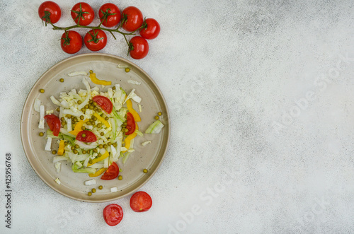 fresh summer vegetable salad with peking cabbage, cherry tomatoes, green peas and yellow bell pepper on a ceramic plate
