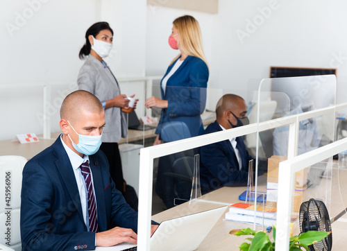 Typical working day in office of an IT company - programmers in protective mask work at a laptop photo