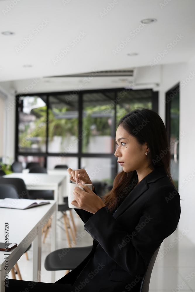 Portrait of thoughtful businesswoman holding coffee cup looking forward through glass window at her workplace. Portrait of thoughtful businesswoman holding coffee cup looking forward through glass window at her workplace.