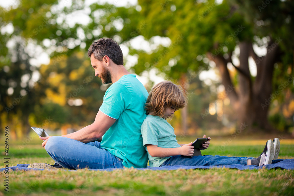 Father and son playing or studying with laptop in the park. Father and son playing or studying with laptop in the park.