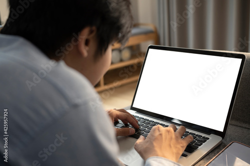 Close up view asian man lying on sofa and surfing internet with computer laptop.