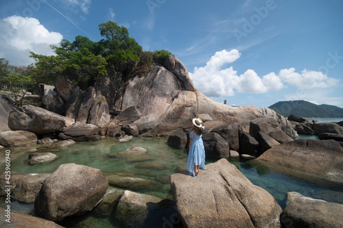 Photography Woman traveler wearing blue dress and straw hat enjoying at Hin Ta and Hin Yai Rocks during summer at Koh Samui Island, Surat Thani Province, Thailand