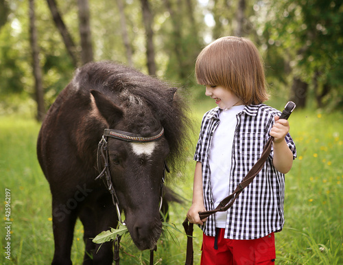 a boy walking with a pony in the forest
