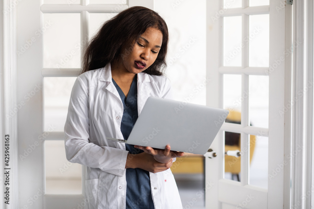Handsome contented African American female doctor working on a laptop. telemedicine Handsome contented African American female doctor working on a laptop. telemedicine
