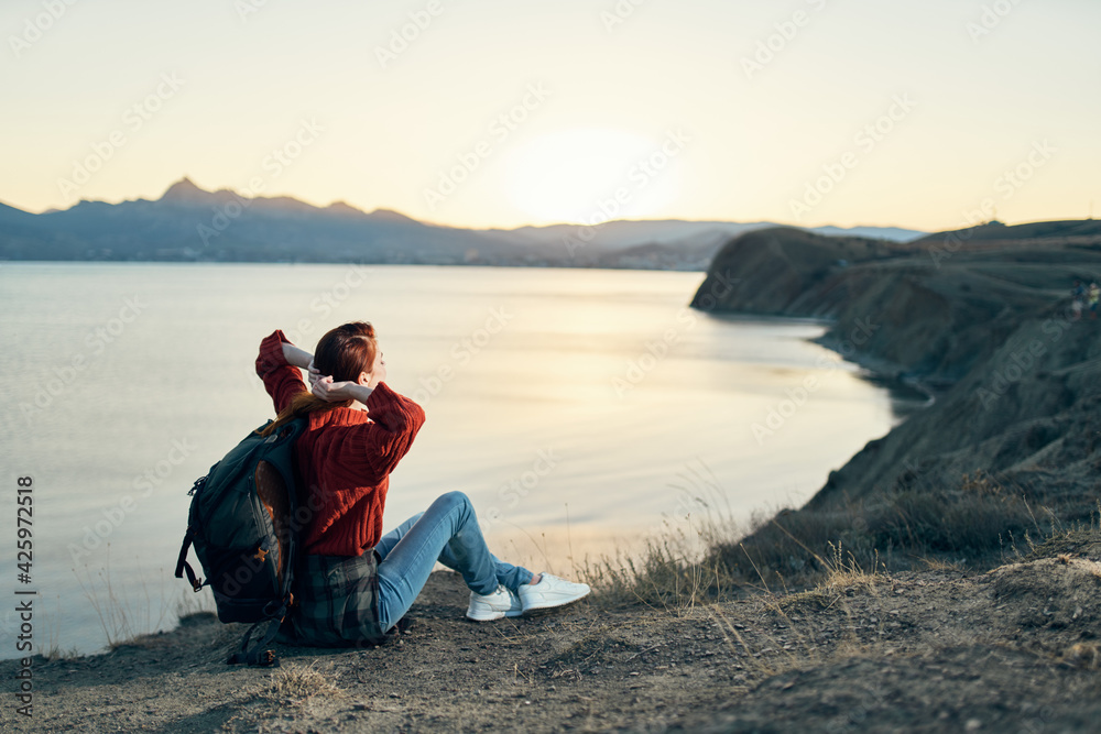 woman tourist with a backpack in the mountains at sunset near the sea top view