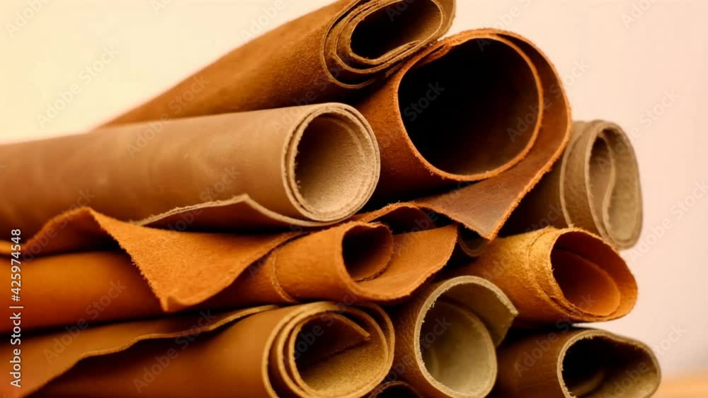 Leather rolls in brown tones on a blurred beige background.Leatherworking.Leather goods material Leather rolls in brown tones on a blurred beige background.Leatherworking.Leather goods material