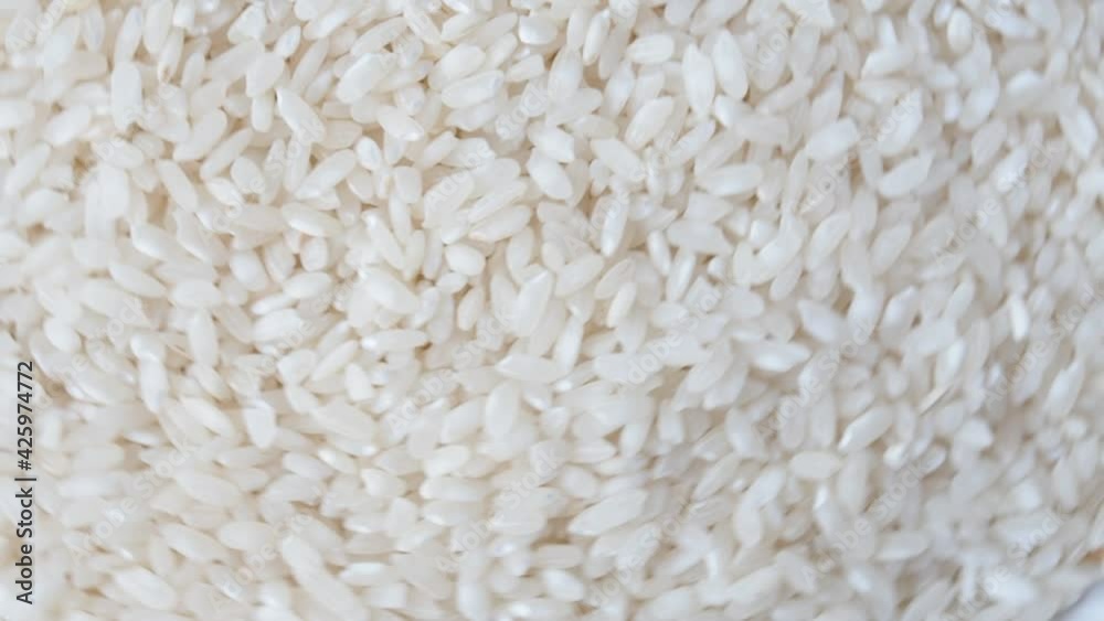 Raw white rice grains rotate. Close up of cereal porridge. Raw white rice grains rotate. Close up of cereal porridge.