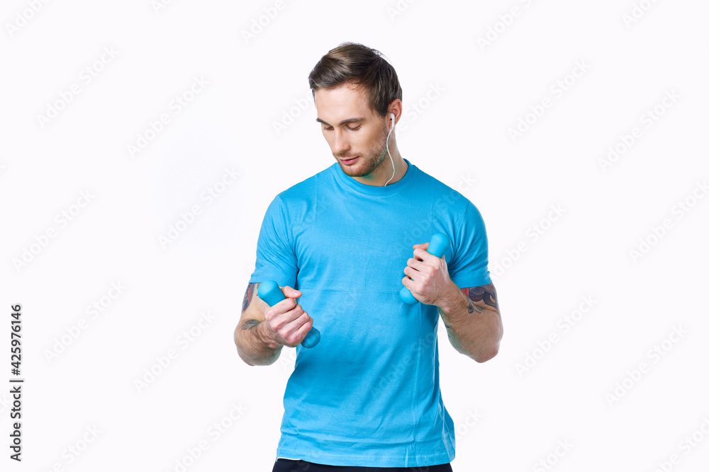 athlete with dumbbells on a light background and blue t-shirt pants tattoo athlete with dumbbells on a light background and blue t-shirt pants tattoo