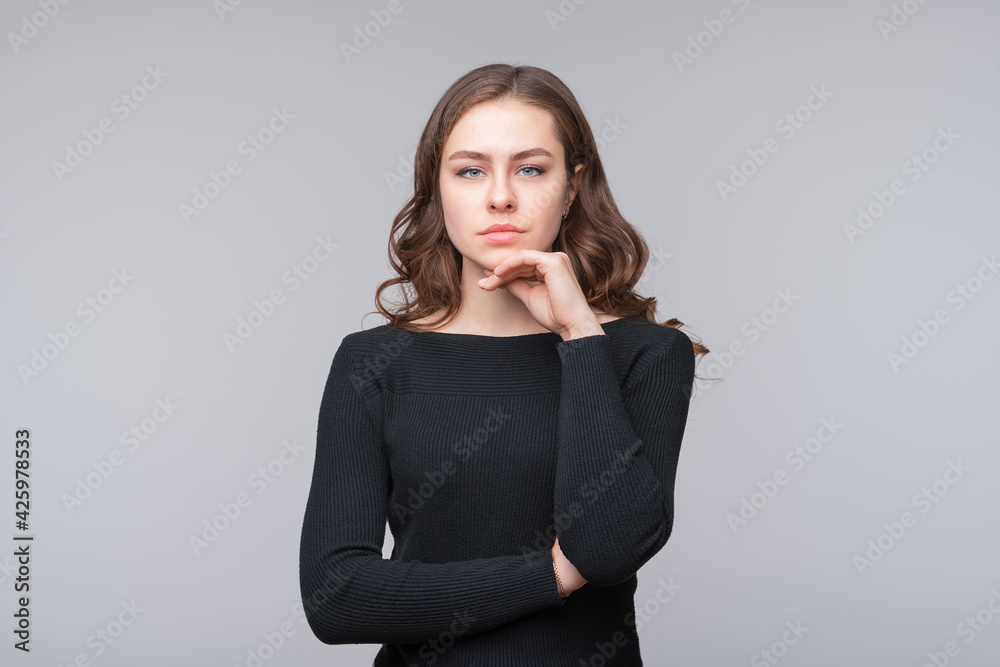 Portrait of cute thinking young woman holding arm on chin wear casual black sweater Portrait of cute thinking young woman holding arm on chin wear casual black sweater