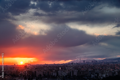 Tehran-Iran skyline at a moody sunset after a heavy storm. with Milad tower and beautiful snow covered mountains and amazing clouds in the background.