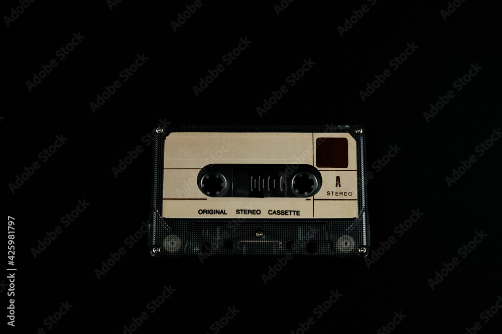 Obraz premium Audio cassette on a black background. Compact tape cassette an analog magnetic tape recording format for audio recording and playback. Copyright protection in the music industry.
