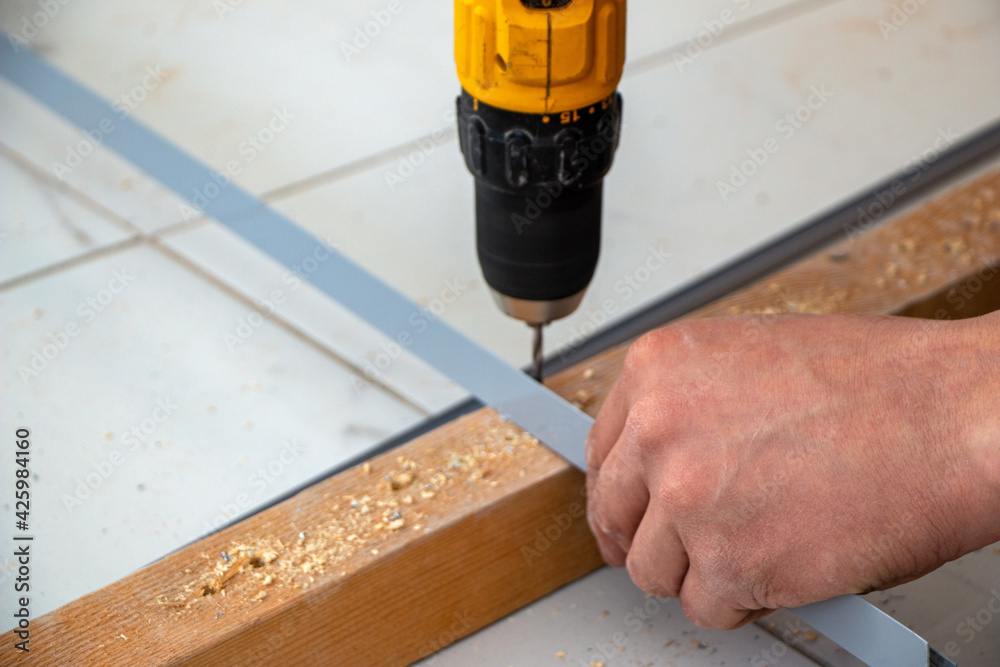 male hands of  construction worker tighten and fix  screws and self-tapping screw  with  electric cordless screwdriver for home improvement and building interior decoration.