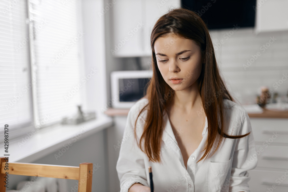 woman in light clothes in the kitchen at the table makeup cosmetics