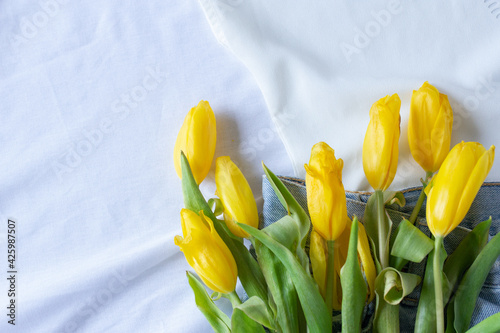 Yellow tulips lying on white sheet background  spring card with copy space
