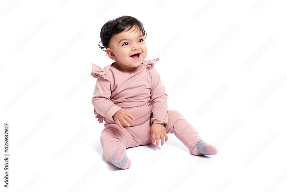 Adorable female baby in lovely pink outfit smiling with mouth open. Attractive little kid sitting on floor and posing, isolated on white studio background. Concept of childhood. Adorable female baby in lovely pink outfit smiling with mouth open. Attractive little kid sitting on floor and posing, isolated on white studio background. Concept of childhood.