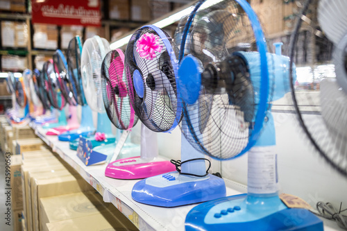 Fan for cooling in an electronics shop,various brands of electrical fans display on a shelf at supermarket in sunny hot summer day,choosing to buy energy efficient appliances,save energy concept