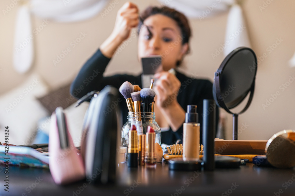Makeup brushes on a table and in the background a woman putting on makeup