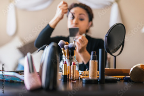 Obraz na płótnie Makeup brushes on a table and in the background a woman putting on makeup w salonie