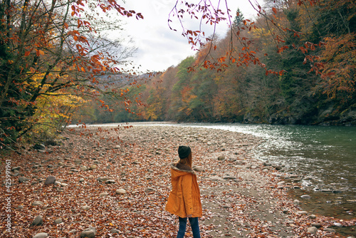 woman in a yellow jacket near the river mountains nature walk © SHOTPRIME STUDIO