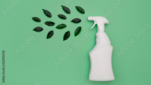 Safe environmental general cleaning, environmentally friendly detergent. Eco bottle with white spray for safe and natural cleansing at home and green leaves on a green background. top view, flat lay