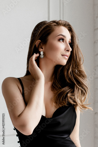Close up portrait of sensual and young woman in black dress posing in studio