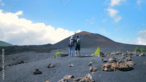 Couple of hikers standing and shooting the landscape at el Chinyero volcano, Tenerife, Canary Islands. Static shot photo