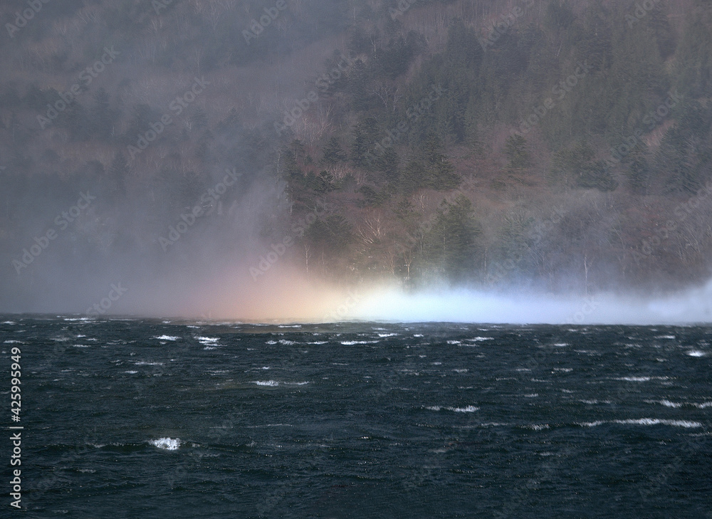 強い風にあおられた湖面に水柱が立つ。太陽の光を受けた水滴が虹を形成していく。虹が出現する瞬間。