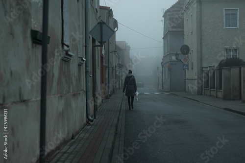 Fototapeta Naklejka Na Ścianę i Meble -  person at the misty streets of the small town