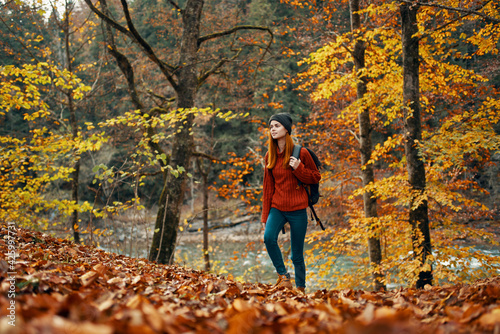 woman tourist walks through the park in autumn with a backpack on her back and tall trees landscape river lake © SHOTPRIME STUDIO