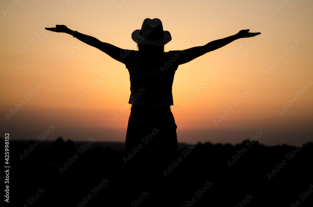girl in a hat in the evening at sunset, early afternoon in the wild, burning sky, peace and quiet alone with nature