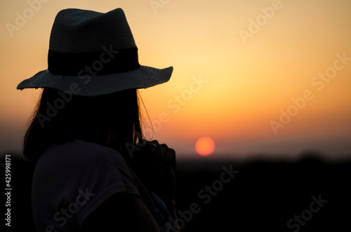 girl in a hat in the evening at sunset, early afternoon in the wild, burning sky, peace and quiet alone with nature