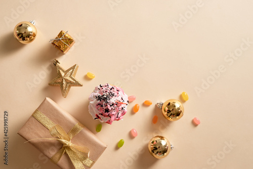 Christmas card. Cupcake with gift boxes, ornament and candies on light yellow background. Holidays.