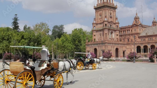 Beautiful Espana Square, in the center of Seville. Pandemic time , with very few tourists. Horse-drawn carriage passing. Camera still and slowly tilt up to the tower.