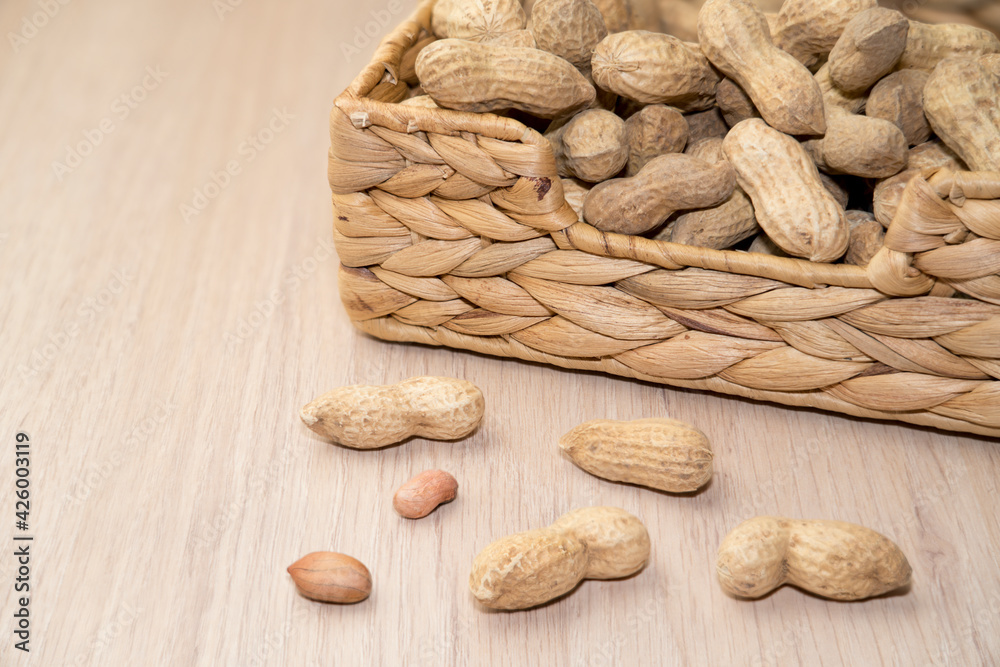 peanuts unpeeled in a basket on a wooden background peanuts unpeeled in a basket on a wooden background