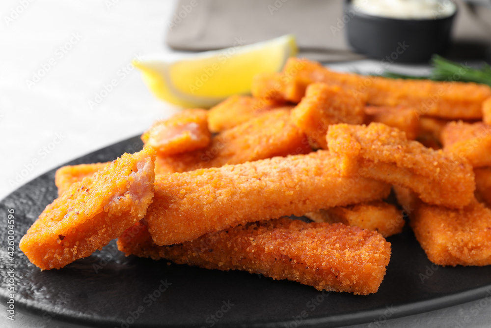 Tasty fresh fish fingers on black plate, closeup Tasty fresh fish fingers on black plate, closeup