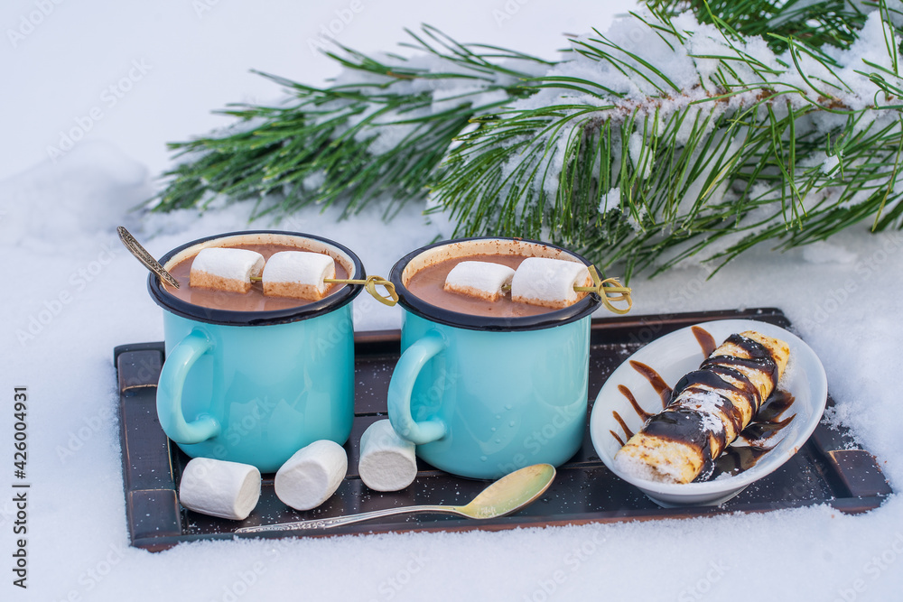 Two hot cocoa drink on a bed of snow and white background, close up Two hot cocoa drink on a bed of snow and white background, close up