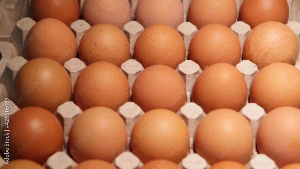 Chicken egg packaging on a blue background. Fresh raw chicken eggs in egg box at the farm or market. A macro. Close-up. Chicken egg packaging on a blue background. Fresh raw chicken eggs in egg box at the farm or market. A macro. Close-up.