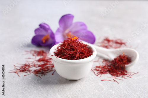 Dried saffron and crocus flowers on grey table, closeup photo