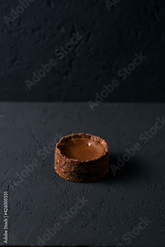 dessert according to the French recipe - a shortbread basket with chocolate flavor filling on a black background