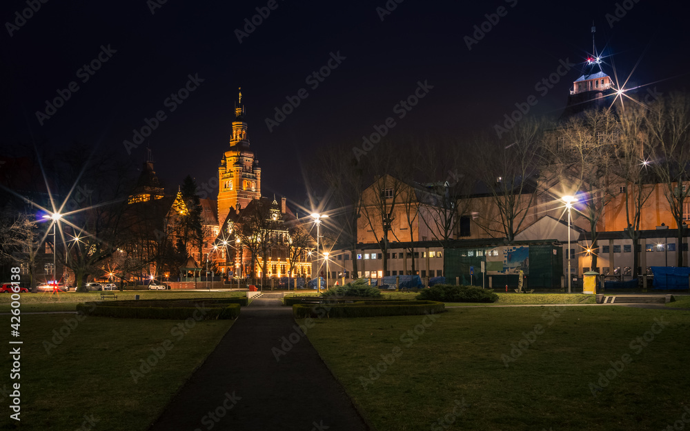 a night shot of the path leading to illuminated old buildings in Szczecin